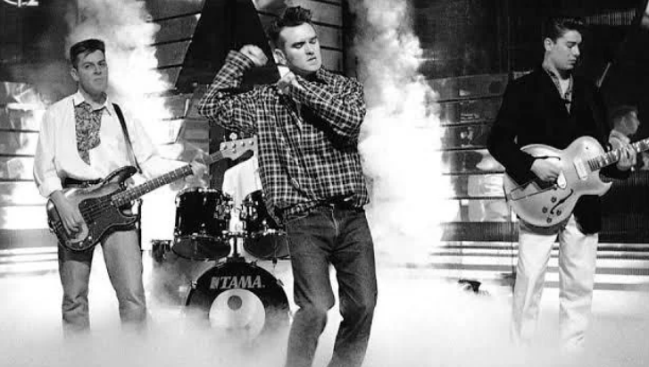 The Smiths performing on a television stage, with Morrissey singing at centre