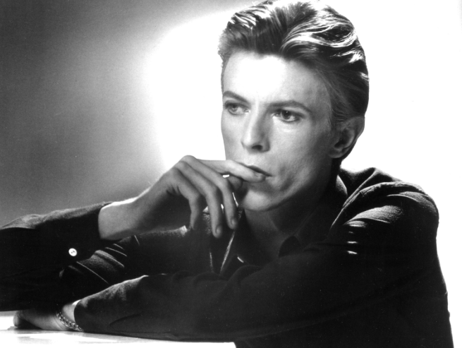 Black-and-white studio portrait of David Bowie resting his chin against his hand