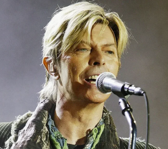 David Bowie singing into a microphone during a live performance
